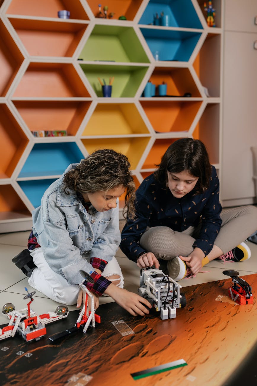 a young man and woman sitting on floor touching a toy robot
