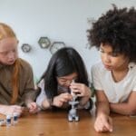 focused little girls with microscope in room